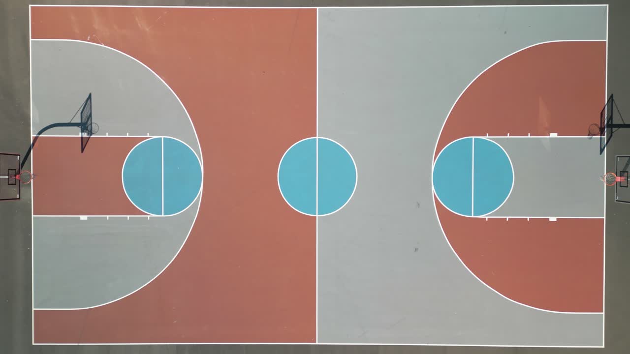 drone aéreo zoom out disparado sobre una colorida cancha de baloncesto en un brillante día soleado