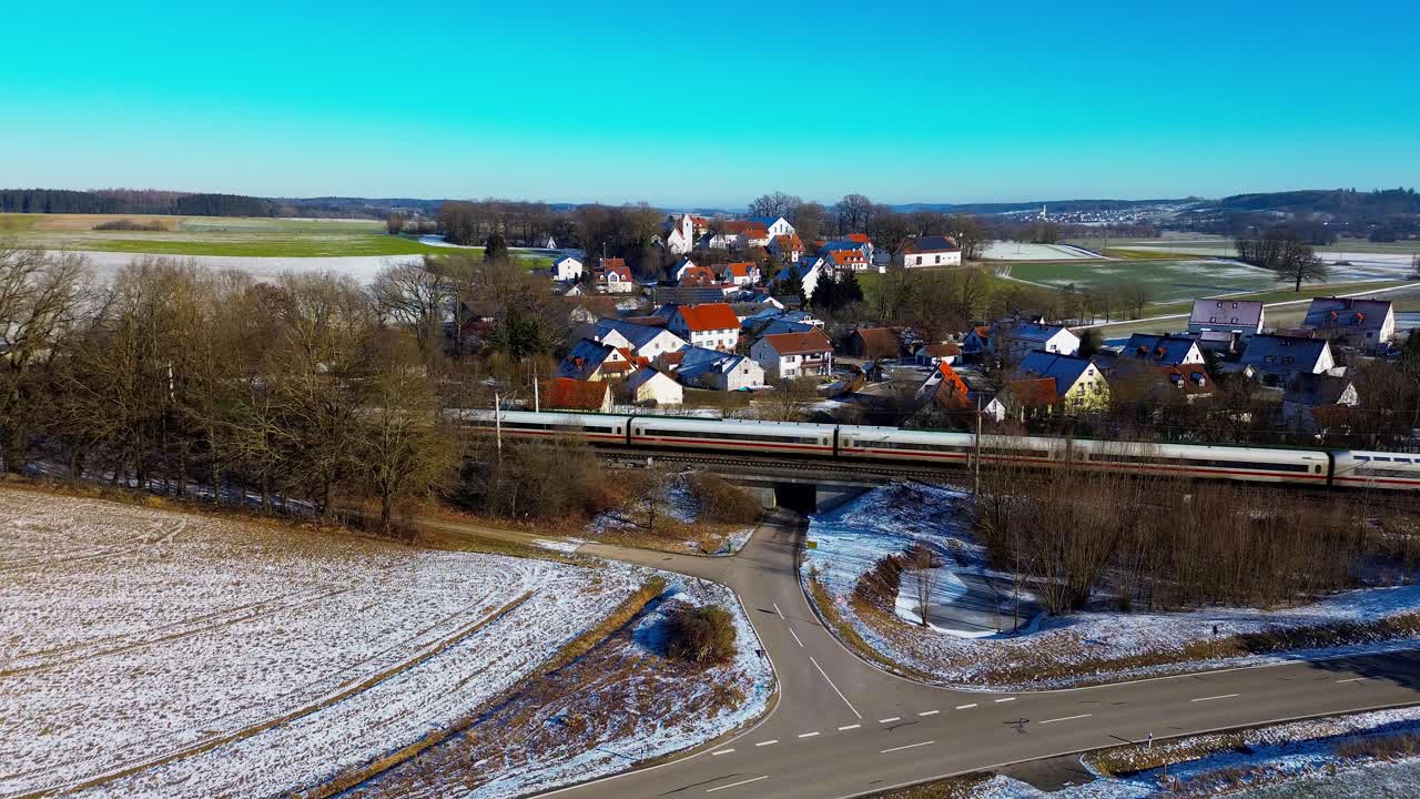 pueblo cubierto de nieve con tren que pasa en el paisaje rural