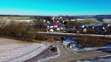 snow-dusted village with passing train in rural landscape