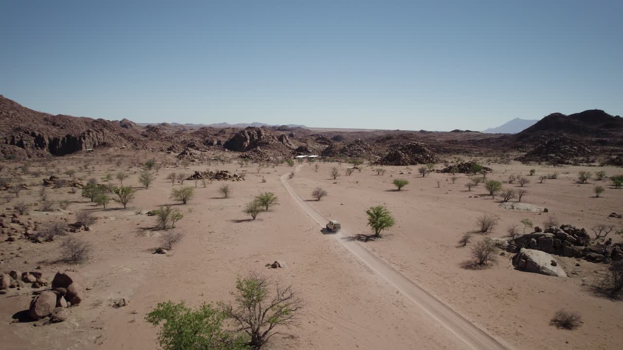 toma de seguimiento de drones cinematográficos de un camión 4x4 en un camino polvoriento, desierto africano