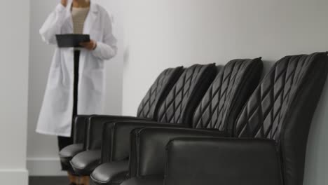 female doctor wearing white coat walking into empty surgery or hospital waiting room