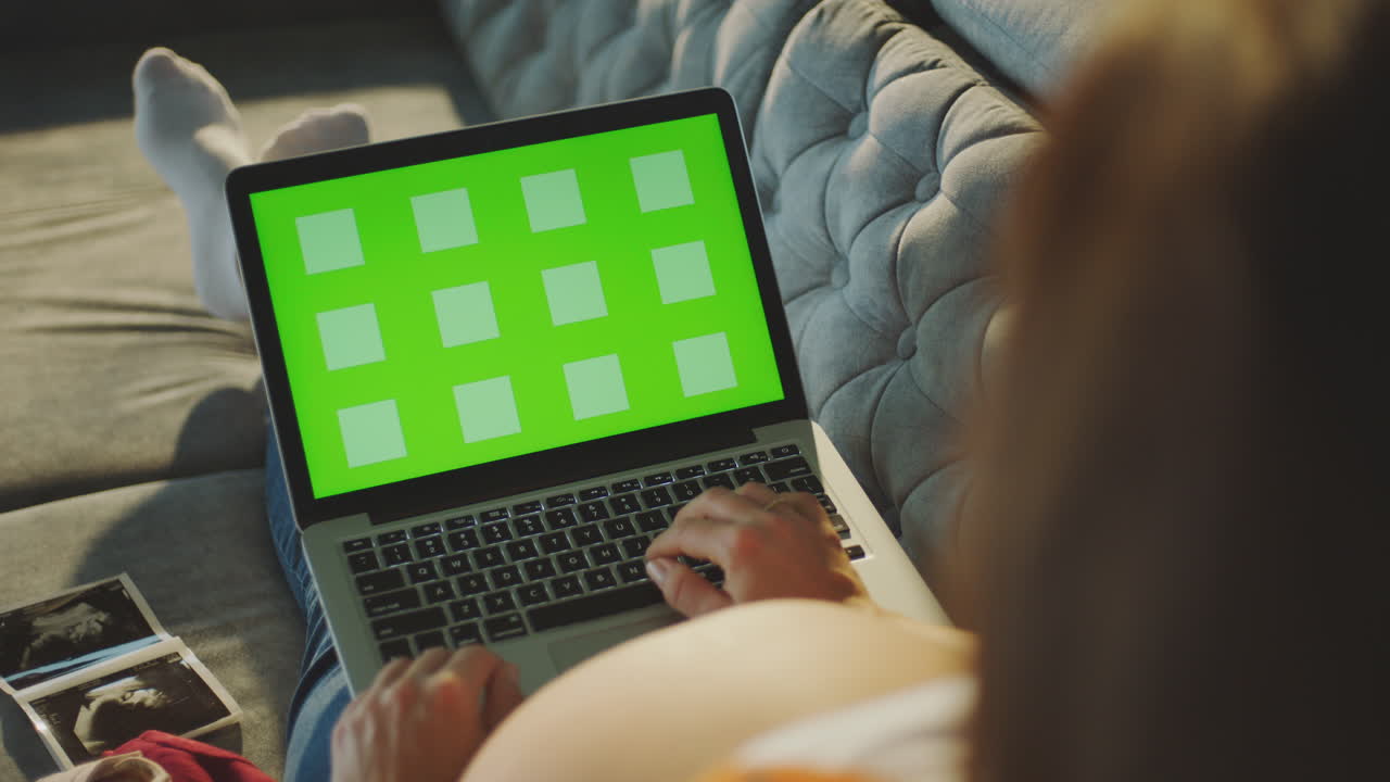 mujer embarazada trabajando en una computadora portátil en casa