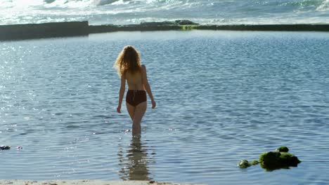 Woman-standing-in-the-sea-at-beach-4k