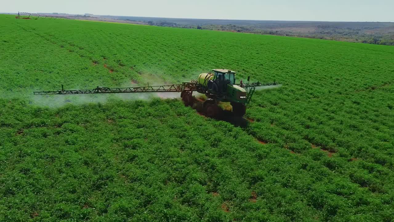 Vista Aerea di un'Irroratrice Agricola al Lavoro in un Campo Coltivato Verde
