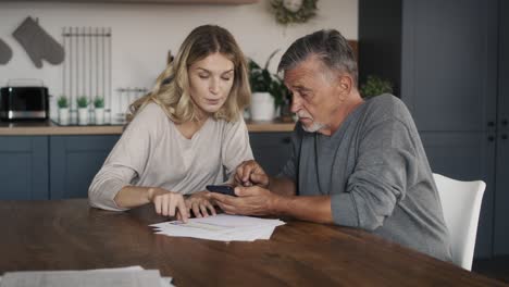 caucasian woman helping senior man with using mobile phone.