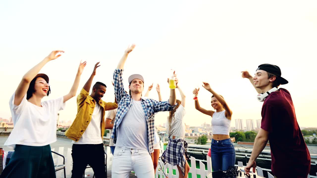 chicas y chicos atractivos estudiantes están bailando en una fiesta al aire libre con dj profesional trabajando con la consola de mezcla. amigos están bebiendo refrescos y divirtiéndose.
