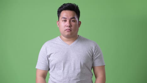 초록색 배경에 젊은 잘생긴 과체중 아시아인