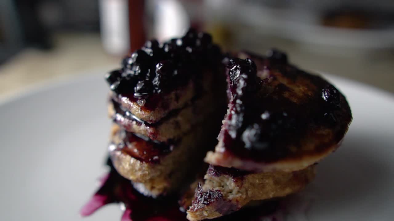 금속 나이프와 포크로 네 개의 쌓인 블루베리 팬케이크를 썰기