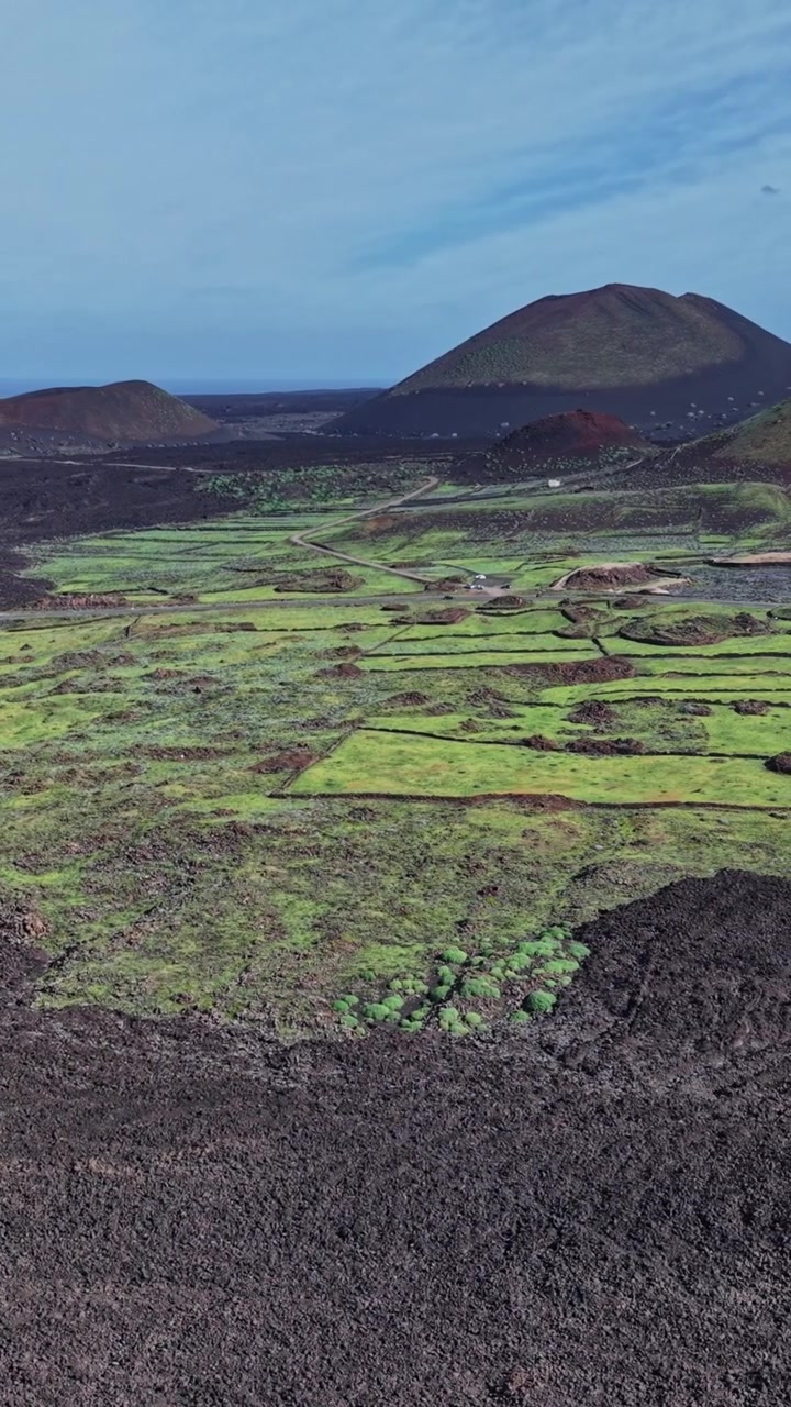 Paesaggio di Lanzarote con colline vulcaniche e campi verdi di giorno