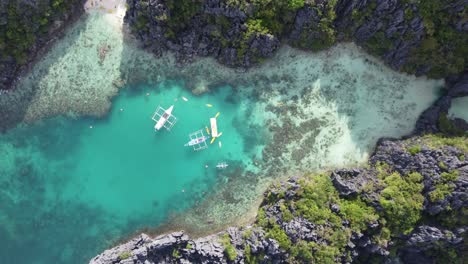 Barcos-Anclados-En-La-Pequeña-Laguna-Turquesa,-Isla-Saltando-El-Nido-Palawan,-Drone