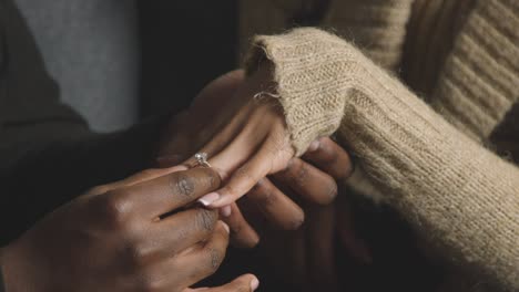 close up of man putting engagement ring on woman's finger as he proposes marriage 1