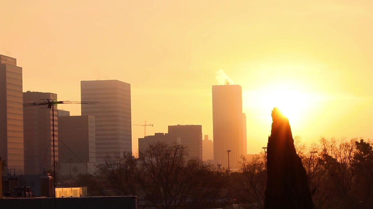 Timelapse de edifícios de Los Angeles com nascer do sol entre as nuvens.
