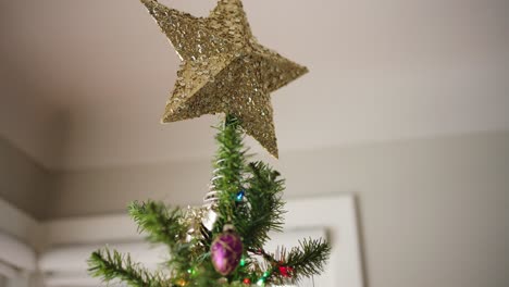 tilt down from gold christmas tree star to ornaments and stockings