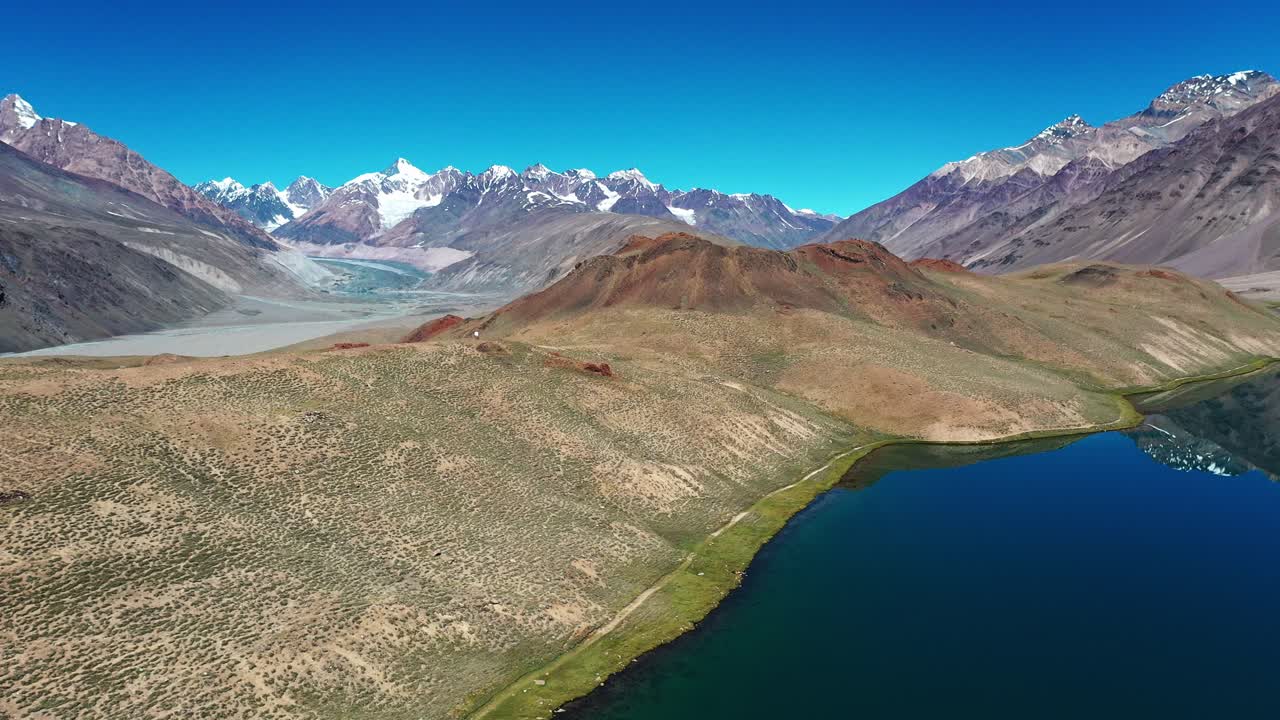 Spiti Vadisi'ndeki Chandratal Gölü fonunda dağları ve buzul nehrini gösteren havadan çekim.