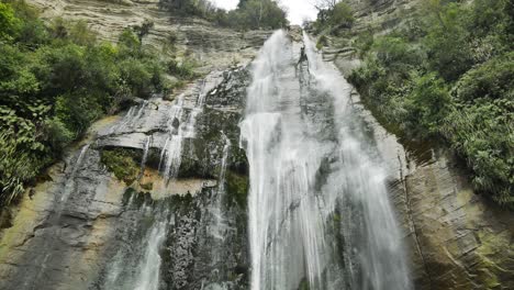 new zealand tall cliff waterfall in hawkes bay, low angle waterfall looking up