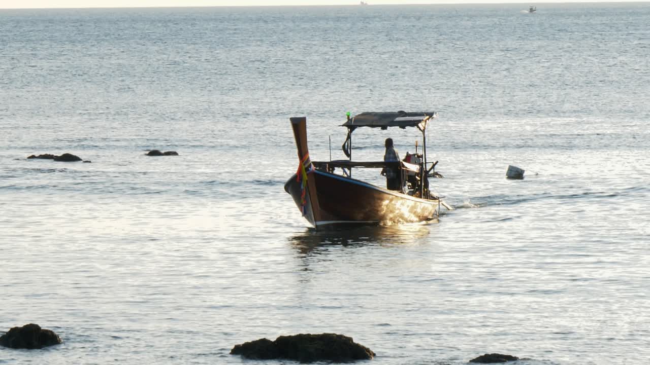 Fisherman sailing fishing boat while sunset shines on sea