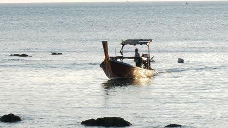 fisherman sailing fishing boat while sunset shines on sea