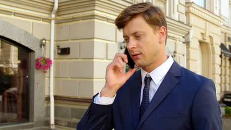 portrait man talking mobile phone outside. guy walking with smartphone outdoors