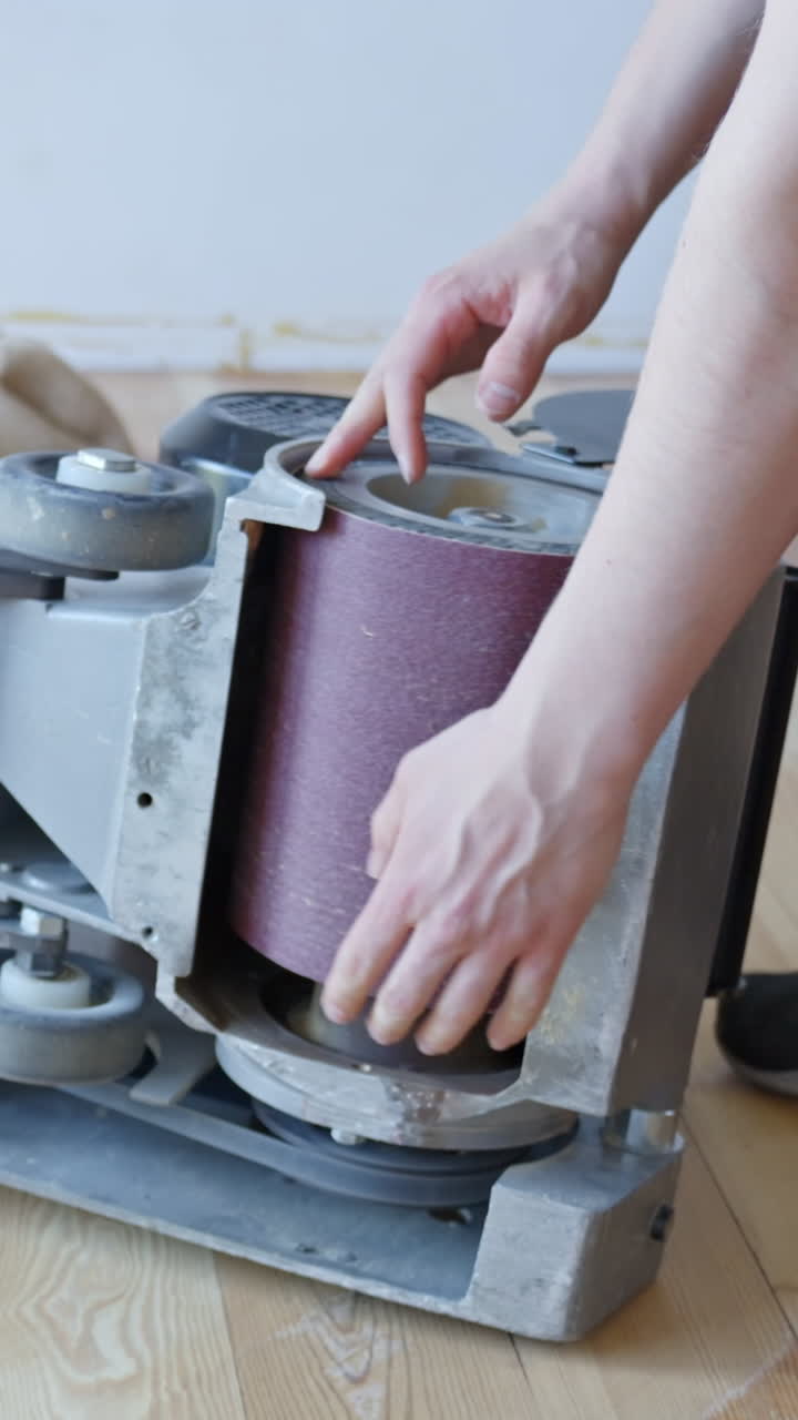 Changing sanding belt on floor sander before vertical sanding pine wood floors