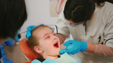 close up of little patient lying on chair with open mouth during dental examination