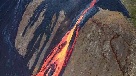 lava flowing down the cliff during volcanic eruption at mount fagradalsfjall, southwest iceland - aerial drone shot