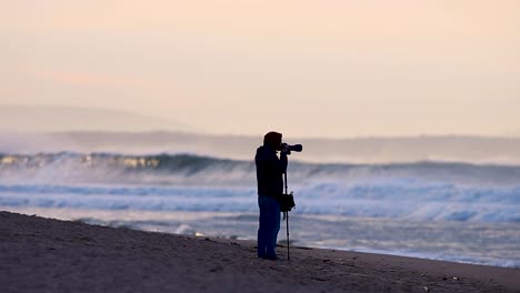 Photographer-with-a-tripod-takes-pictures-of-a-Portuguese-beach-at-sunrise