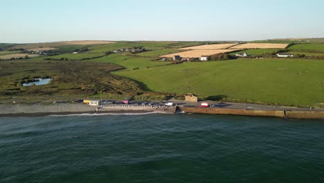rural ireland, garretstown beach and coastal farms from above. aerial county cork. waves and holiday camper vans.