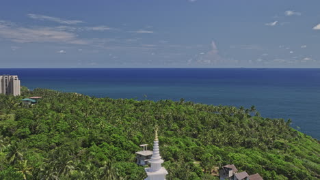 unawatuna sri lanka aerial v12 reverse flyover hillside, revela la pagoda de la paz japonesa en la colina de rumassala y la playa de la selva tropical y las exóticas vistas al océano de verano - filmado con mavic 3 cine - abril 2023