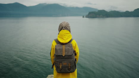 woman hiking in a yellow raincoat, scenic landscape view