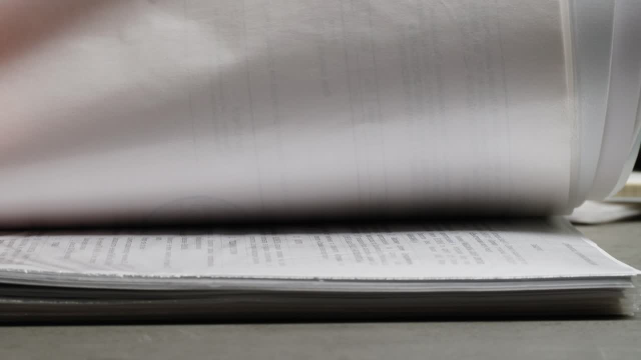 Close-up of Hand Flipping Through Documents on an Office Desk