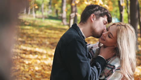 romantischer mann, der frau mit langen blonden haaren im wald anhebt