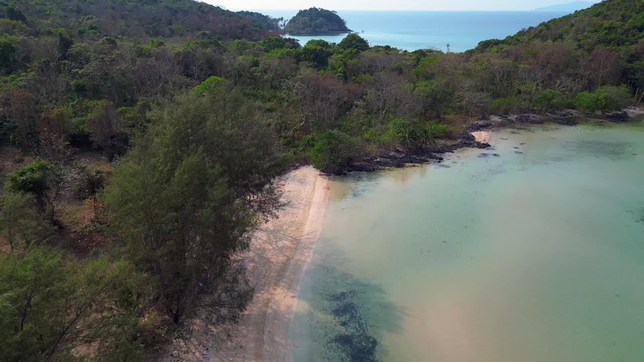tropical vegetation meeting crystal clear water on natural beach Koh Mak island, Thailand. Marvelous aerial view flight static tripod hovering drone
