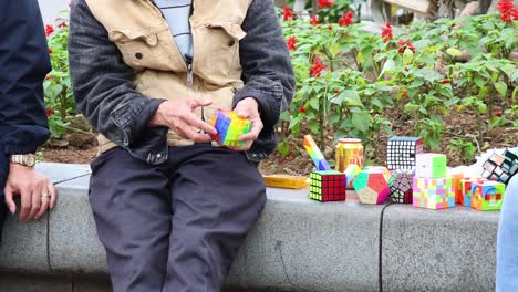 elderly man solving rubik's cube in public park