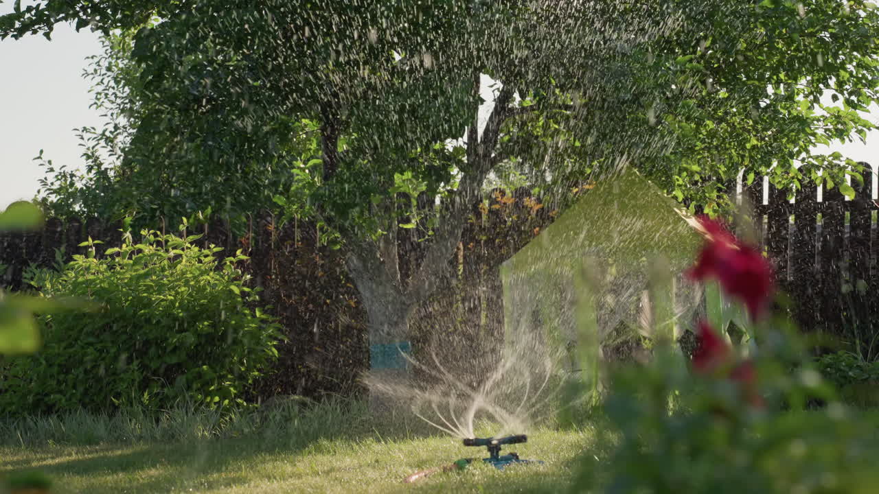 Water Sparkles Shine, Sprinkler Releases Delicate Water Across Lush Green Scenery In Sunlight, Water Droplets Shimmer On Vibrant Grass As Sprinkler Disperses Fine Mist Under Bright Sunshine