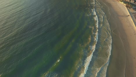 aerial drone footage captures serene waves gently rolling onto sandy shore at beach in iceland, creating calming and rhythmic scene as water meets coastline