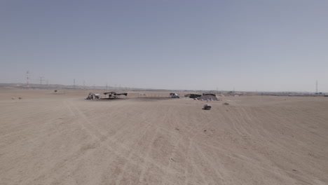 bedouin residential tents without a permit in a remote and desert area, near a highway and large power poles, dry land without crops, push in shot