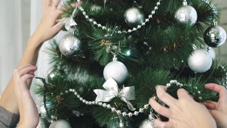 women sitting near christmas tree. girls in hat decorates the christmas tree in the room while sitting on floor