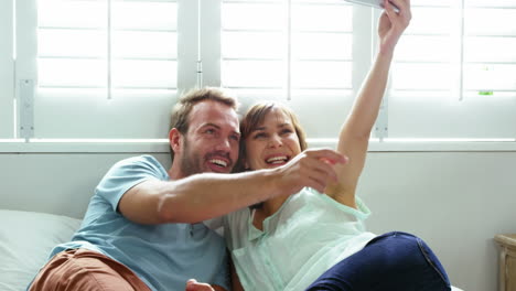 cute couple lying on bed taking some photos with smartphone