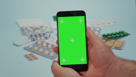 man hand using smart phone, green screen and medical pills