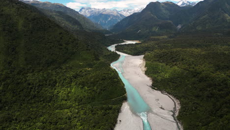 vista aérea hacia adelante de un desfiladero en montañas verdes y un río azul que lo atraviesa