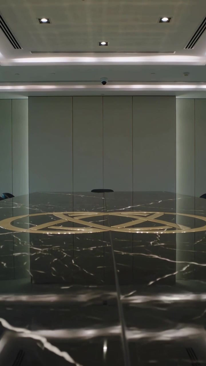 Video vertical: Cámara moviéndose a lo largo de una mesa de mármol brillante, centrando un emblema dorado y enmarcando paneles.