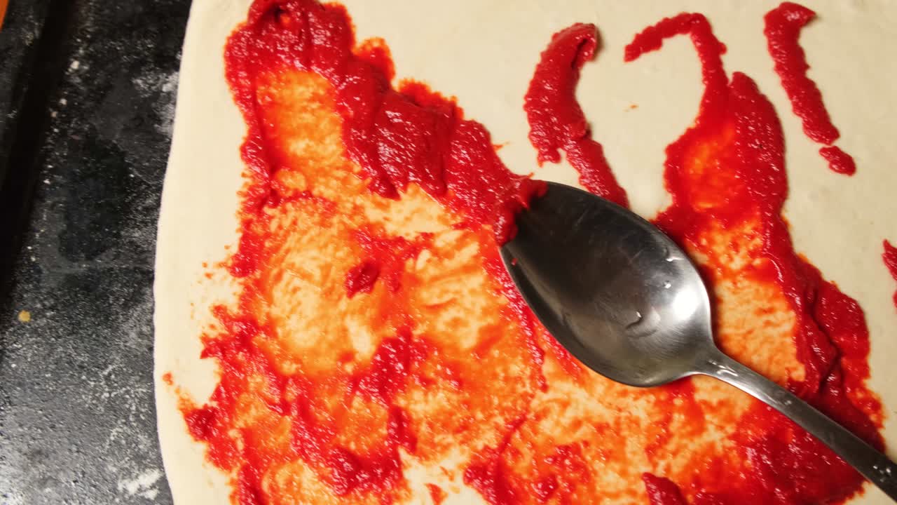 집에서 피자 반죽 위에 토마토 소스를 뿌려라.