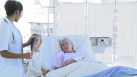 female doctor talking to a senior woman in bed and little girl