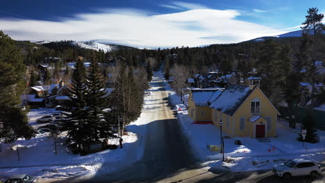 Aerial-forward-view-of-mountain-road-with-passing-cars-and-snow-around