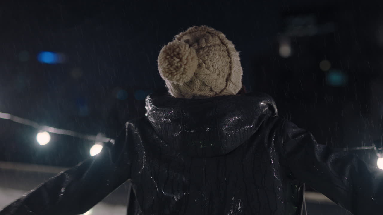 красивая молодая женщина танцует под дождем на крыше ночью, наслаждаясь нежными каплями дождя, касающимися кожи.