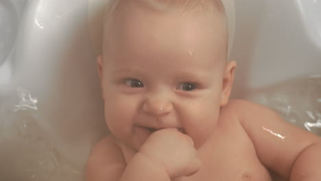 a closeup of an adorable baby girl smiling in bathtub