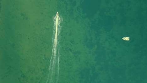 Aerial-top-down-showing-splashing-jet-ski-driving-with-high-speed-over-the-sea