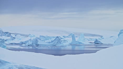 Gran-Puesta-De-Sol-Del-Paisaje-Marino-Del-Iceberg-De-La-Antártida,-Grandes-Icebergs-Azules-Masivos-Con-Formas-Asombrosas-Y-Nubes-Dramáticas-Y-Cielo-En-El-Paisaje-Invernal-Del-Amanecer-En-La-Península-Antártica-En-Una-Escena-Helada