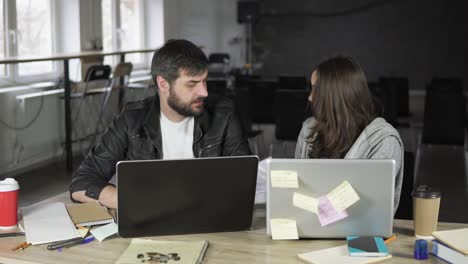 young office workers arguing in front of their laptops. woman showing papers being very angry. slow motion