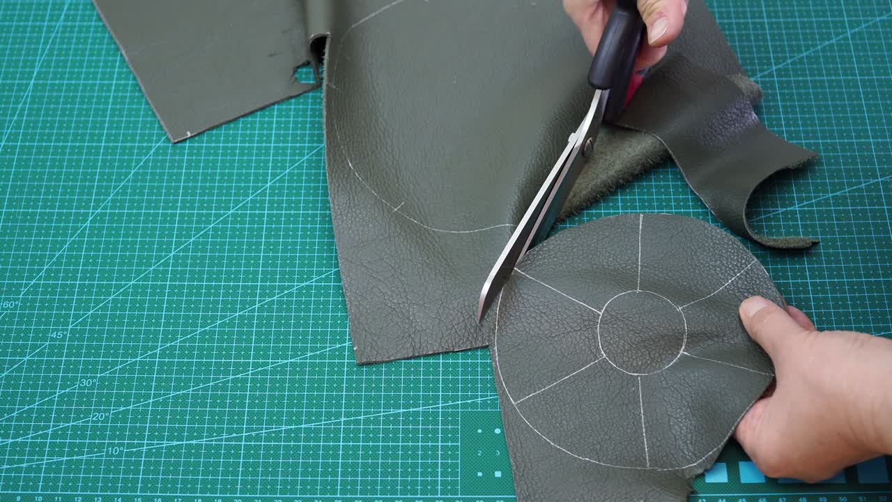 ремесленник режет деталь мешка из кожи в соответствии с нарисованным эскизом